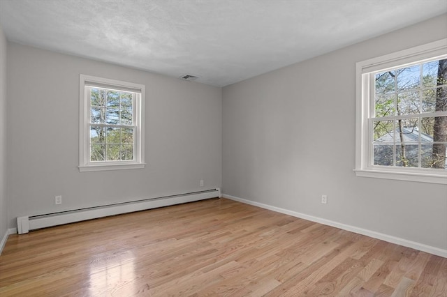 unfurnished room featuring light wood-style floors, baseboards, baseboard heating, and visible vents
