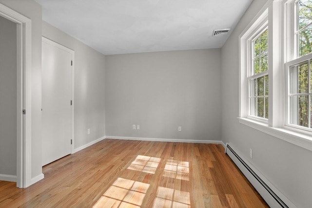 interior space featuring baseboards, light wood finished floors, a baseboard heating unit, and multiple windows
