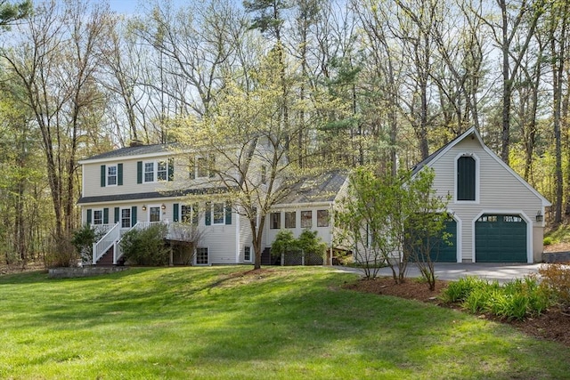 view of front facade featuring stairs, a front lawn, driveway, and a chimney