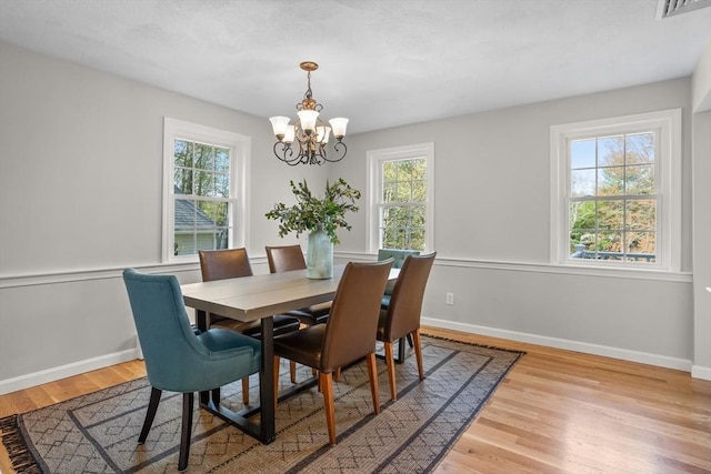 dining room with baseboards, an inviting chandelier, a wealth of natural light, and light wood-type flooring