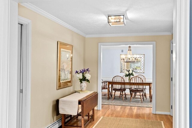 dining room featuring light wood-type flooring, baseboards, a chandelier, and crown molding