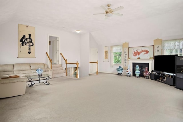 living area with lofted ceiling, carpet floors, ceiling fan, and a glass covered fireplace