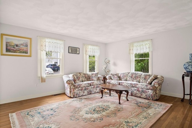 living area featuring plenty of natural light, wood finished floors, and baseboards
