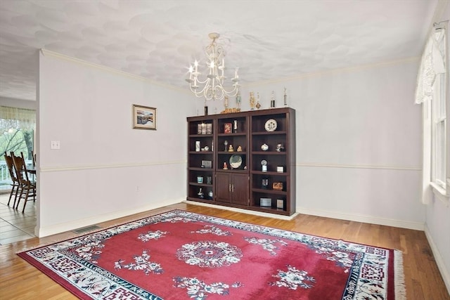 dining space featuring a chandelier, wood finished floors, baseboards, and ornamental molding