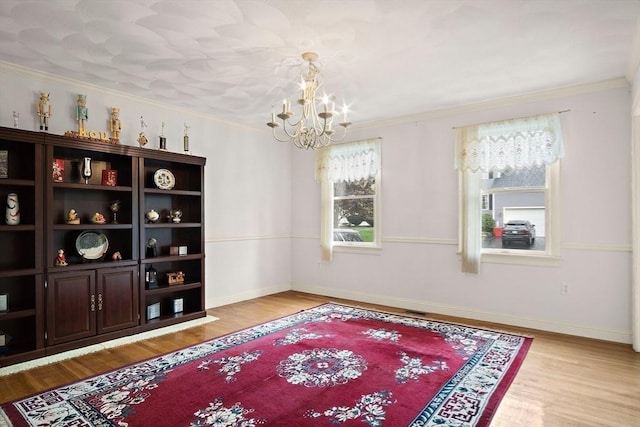 unfurnished room with a chandelier, wood finished floors, ornamental molding, and baseboards