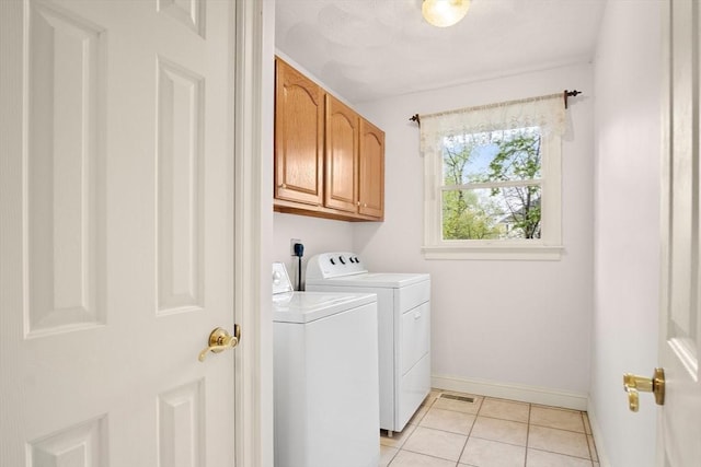 washroom featuring washing machine and dryer, cabinet space, baseboards, and light tile patterned floors