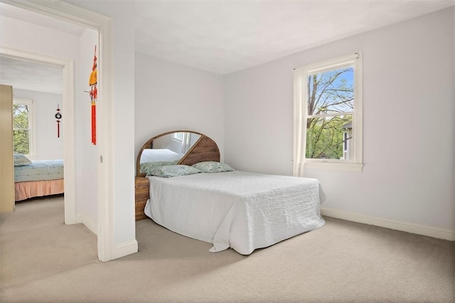 carpeted bedroom featuring baseboards and multiple windows