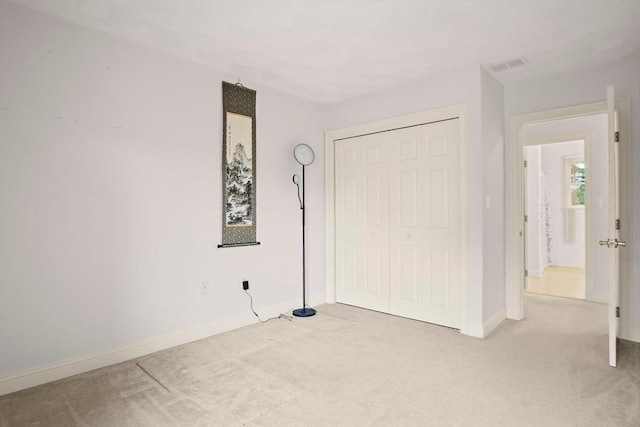 unfurnished bedroom featuring light colored carpet, baseboards, and a closet