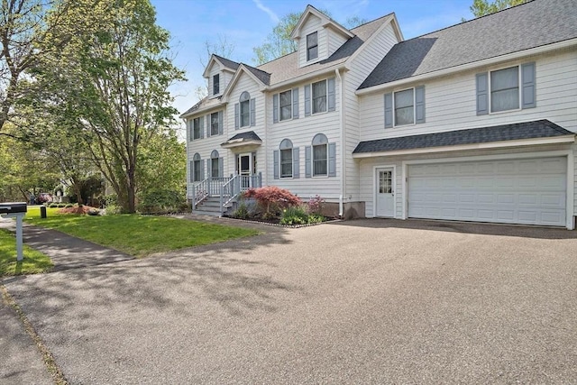 view of front of house featuring driveway, an attached garage, a front lawn, and a shingled roof