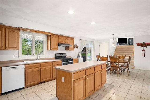 kitchen with stainless steel gas range, white dishwasher, a sink, under cabinet range hood, and light tile patterned floors