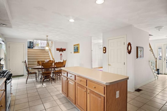 kitchen with stainless steel gas range oven, light tile patterned floors, a center island, recessed lighting, and light countertops