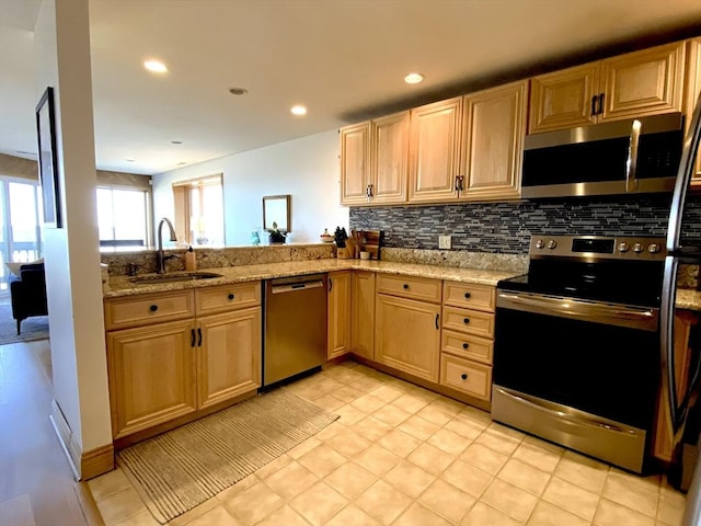 kitchen with light stone countertops, light tile patterned floors, stainless steel appliances, and sink