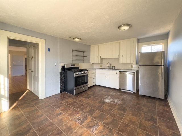 kitchen featuring sink, a textured ceiling, appliances with stainless steel finishes, white cabinets, and backsplash