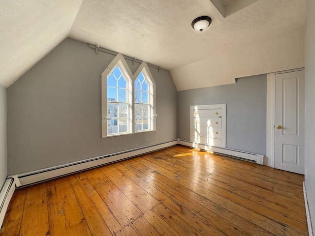 additional living space featuring lofted ceiling, hardwood / wood-style floors, and a textured ceiling