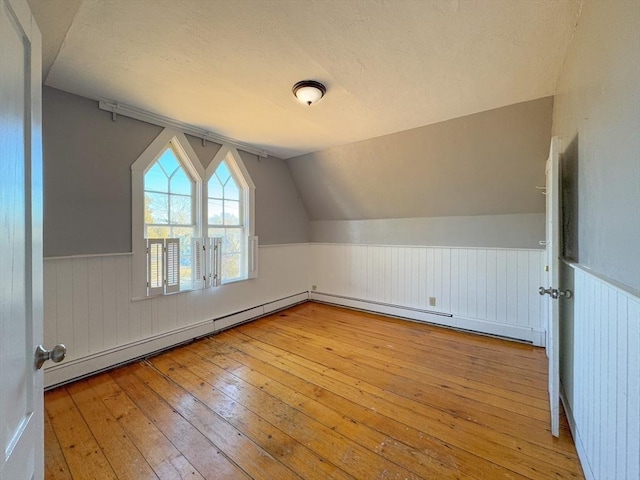 additional living space with vaulted ceiling, light hardwood / wood-style floors, and baseboard heating