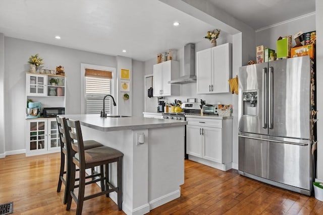 10 Atkins Ave, Lynn, MA 01904 - kitchen with appliances with stainless steel finishes, wall chimney range hood, a sink, light wood finished floors, and white cabinets