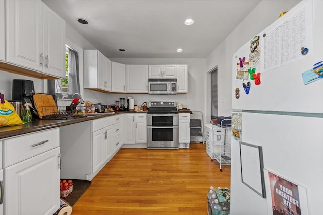 10 Atkins Ave, Lynn, MA 01904 - kitchen featuring appliances with stainless steel finishes, dark countertops, white cabinetry, light wood-style floors, and recessed lighting