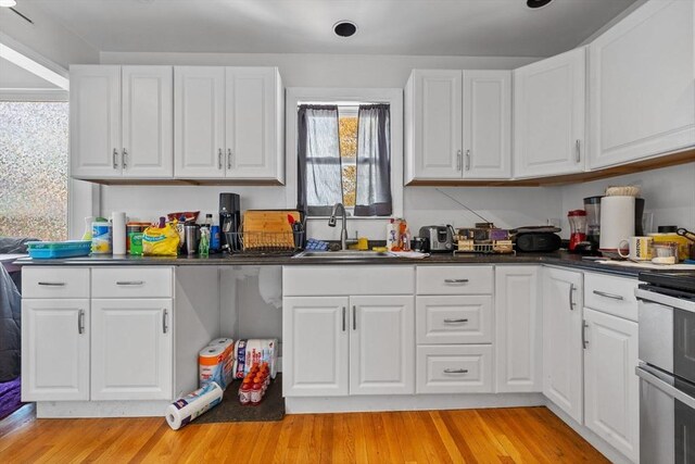 10 Atkins Ave, Lynn, MA 01904 - kitchen with a sink, dark countertops, white cabinetry, range, and light wood-style floors