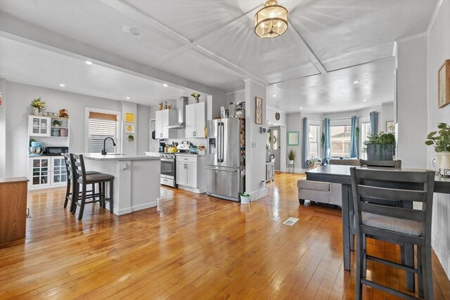 10 Atkins Ave, Lynn, MA 01904 - kitchen with appliances with stainless steel finishes, a sink, a breakfast bar area, white cabinets, and light wood-style floors