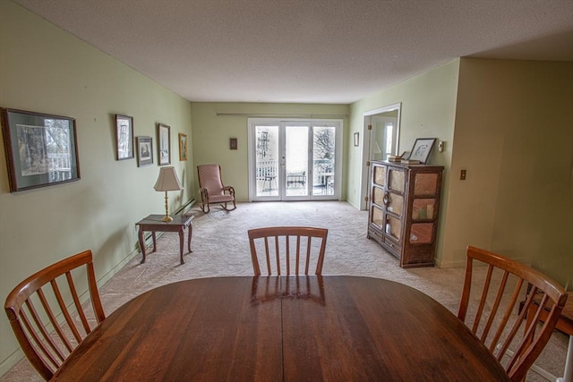 dining space featuring a textured ceiling, french doors, baseboards, and light colored carpet