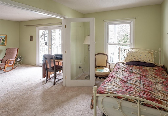 bedroom featuring access to exterior, light colored carpet, french doors, and multiple windows