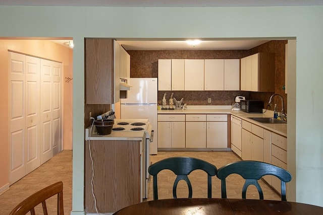 kitchen with light countertops, backsplash, a sink, and under cabinet range hood