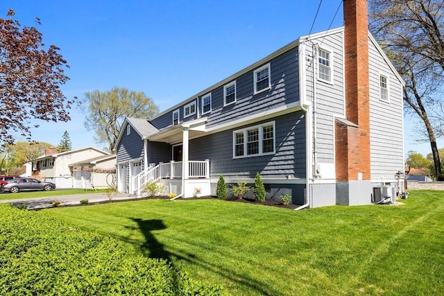 8 Whispering Hill Rd, Woburn, MA 01801 - view of front facade with a chimney, central air condition unit, a front lawn, and driveway