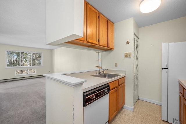 kitchen with a sink, a baseboard heating unit, white appliances, and light countertops