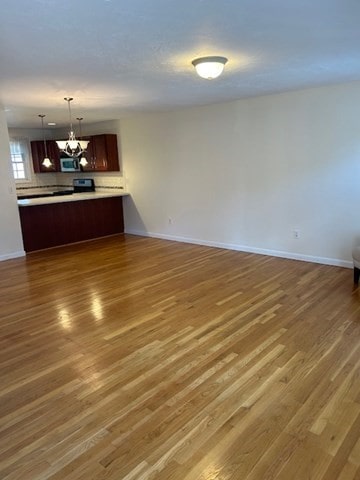 unfurnished living room with a notable chandelier and dark wood-type flooring