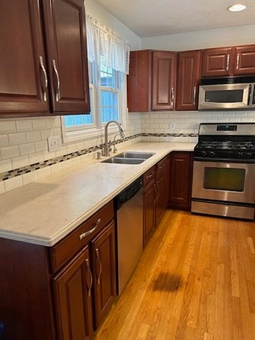 kitchen with decorative backsplash, sink, stainless steel appliances, and light wood-type flooring