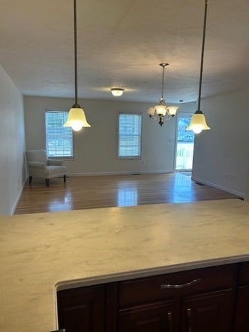 kitchen featuring decorative light fixtures, dark brown cabinetry, wood-type flooring, and a chandelier