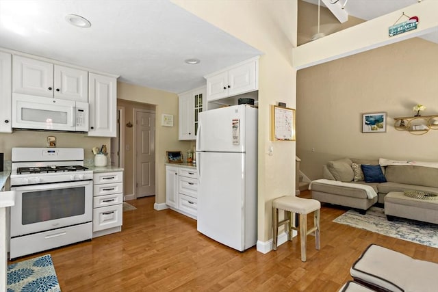 kitchen with white cabinets, light wood-type flooring, and white appliances