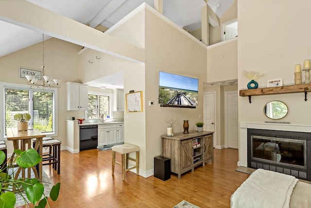 living room with light hardwood / wood-style flooring, high vaulted ceiling, and a notable chandelier