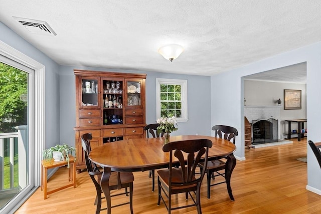 382 Tilden Rd, Scituate, MA 02066 - dining room with light wood-style flooring, a textured ceiling, and a fireplace