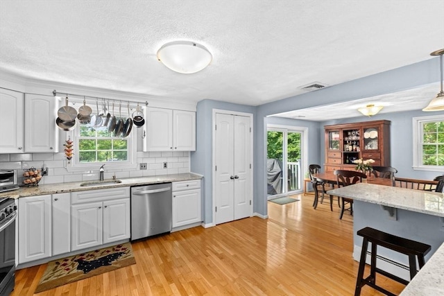 382 Tilden Rd, Scituate, MA 02066 - kitchen featuring stainless steel appliances, decorative backsplash, light wood finished floors, white cabinetry, and a textured ceiling