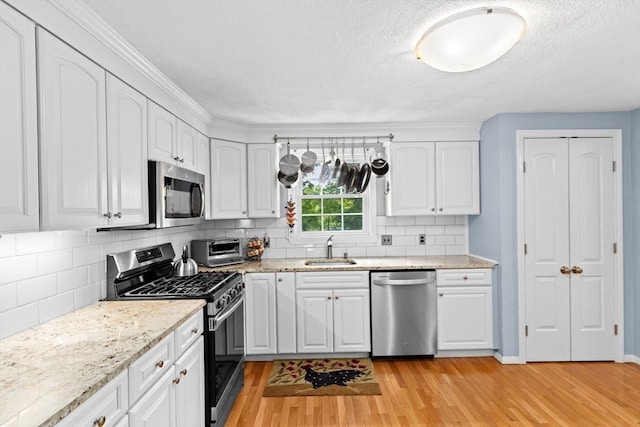382 Tilden Rd, Scituate, MA 02066 - kitchen with stainless steel appliances, light wood-type flooring, white cabinetry, a textured ceiling, and light stone countertops