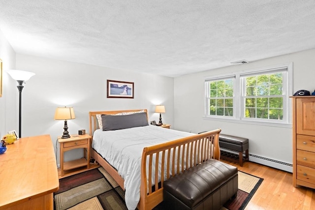 382 Tilden Rd, Scituate, MA 02066 - bedroom featuring wood finished floors, a textured ceiling, and a baseboard heating unit