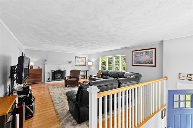382 Tilden Rd, Scituate, MA 02066 - living room with a textured ceiling, light wood-style floors, a fireplace with raised hearth, and crown molding