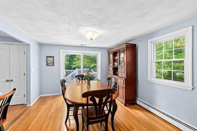 382 Tilden Rd, Scituate, MA 02066 - dining area featuring baseboard heating, light wood finished floors, and a textured ceiling