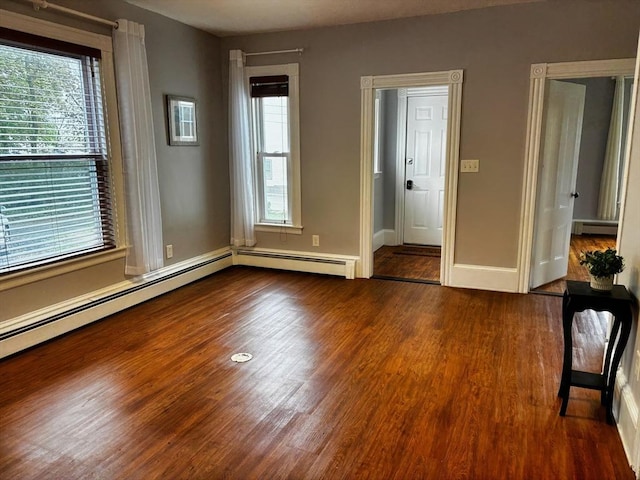 unfurnished room featuring wood finished floors, baseboard heating, and baseboards