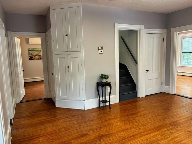 interior space featuring wood finished floors, baseboard heating, baseboards, and stairs