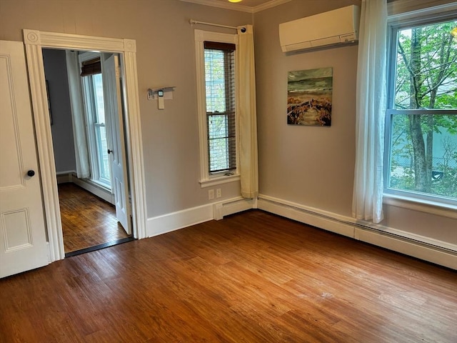 unfurnished room featuring an AC wall unit, wood finished floors, plenty of natural light, and ornamental molding