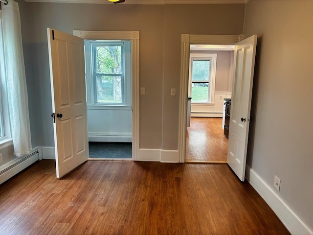 unfurnished bedroom with wood finished floors, baseboards, and a baseboard radiator