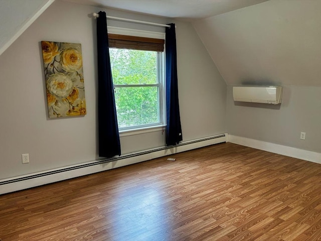 additional living space featuring a wall mounted air conditioner, baseboard heating, lofted ceiling, wood finished floors, and baseboards