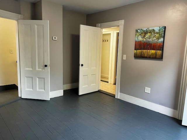 unfurnished bedroom featuring baseboards and dark wood-style floors