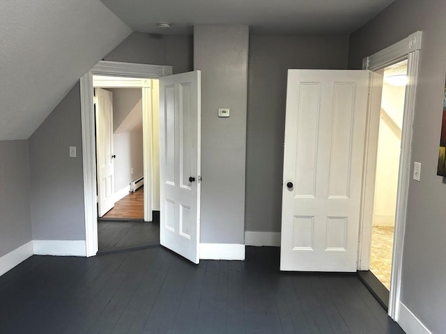 additional living space featuring baseboard heating, baseboards, dark wood-style floors, and lofted ceiling