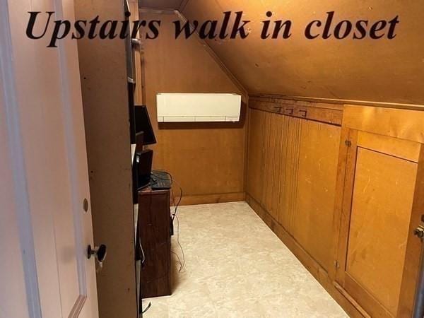 additional living space with vaulted ceiling, wooden walls, and a wall mounted AC