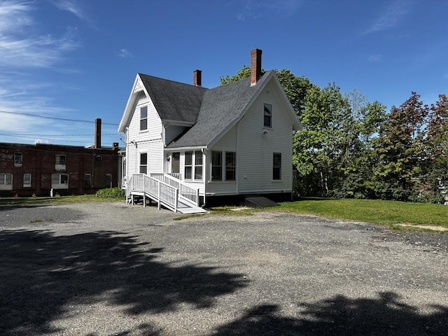 view of home's exterior with a chimney and roof with shingles