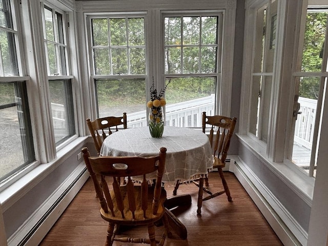 sunroom / solarium with baseboard heating, a baseboard heating unit, healthy amount of natural light, and wood finished floors