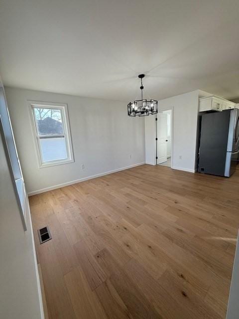 unfurnished dining area featuring a chandelier and light wood-type flooring